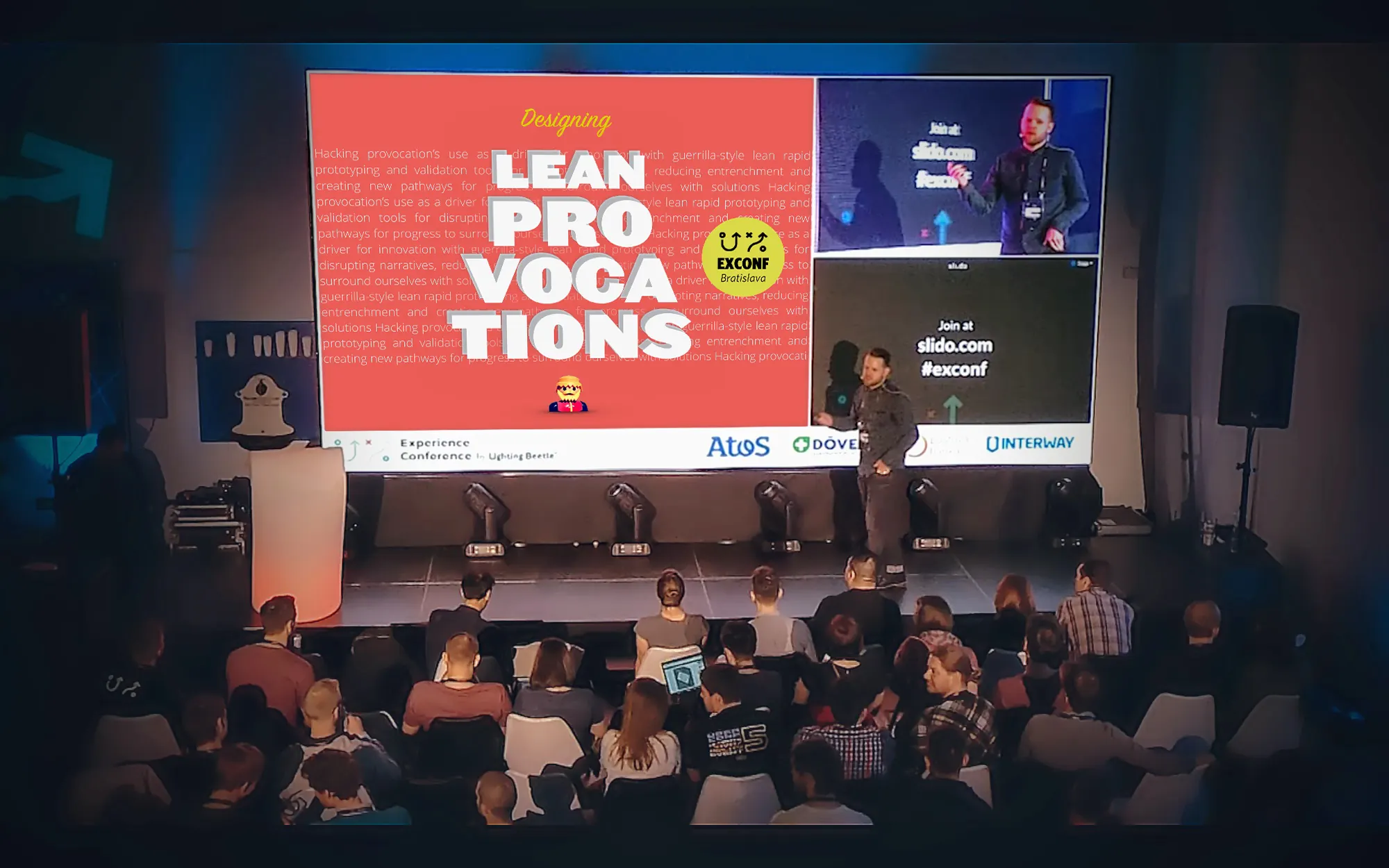 Ryan Haney presenting Designing Lean Provocations on stage at ExConf 2017 in Bratislava, with a large conference screen behind him.